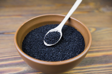 Black cumin (nigella sativa or kalonji) seeds in spoon on wooden background, selective focus