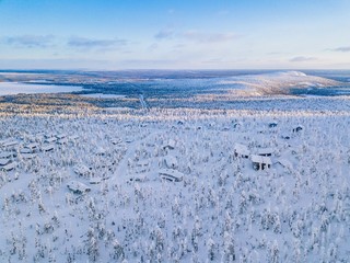 Fototapeta na wymiar Aerial view of winter forest with frosty trees, rural road and village in Finland