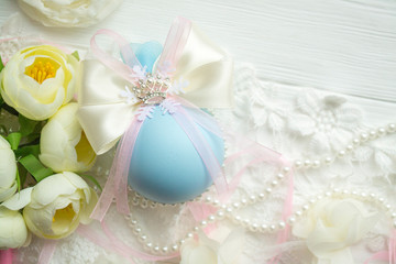 winter vacation. New Year's toys made by hand. Christmas ball in blue color with a bow of satin ribbon, lace, brooch crown, flowers lies on a white wooden background