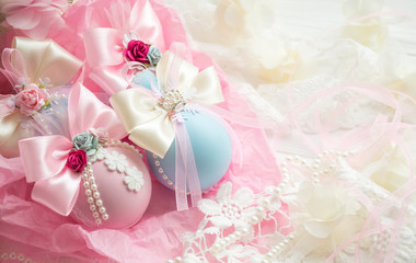 winter vacation. New Year's toys made by hand. a set of pink, blue Christmas balls with a bow of satin ribbon, lace, pearls, flowers lies in paper on a white wooden background