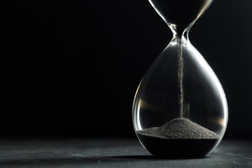 Hourglass on dark background - obrazy, fototapety, plakaty