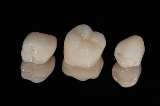 Ceramic dental crowns on the mirror, chewing teeth