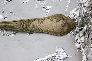 Detail of an old silver spoon in a salt bath with aluminium foil to clean it from stains and making it shiny again. Old fashioned way of cleaning precious silverware