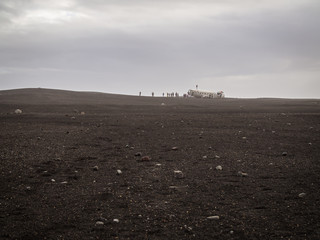Turists on the abandoned crashed plane in Iceland in black sand desert
