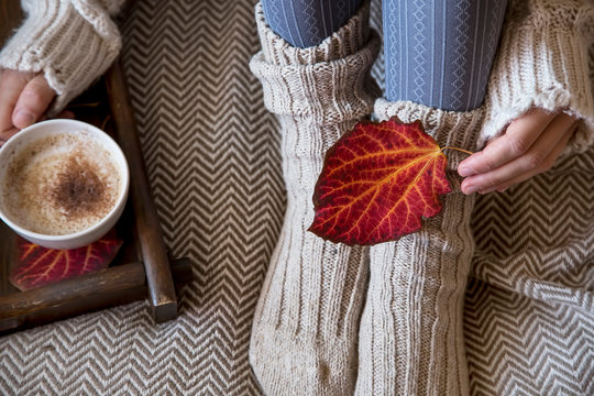 Cozy fall indoor female with woolen socks and coffee cup, soft cozy bed blanket