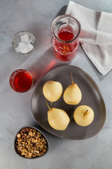 Japanese autumn fruits, pears on a plate on the background of a jug of cranberry juice and mix of nuts.