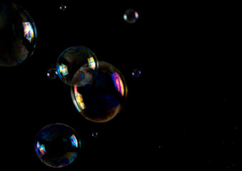 Multicolored soap bubbles close up on a black background, similar to planets