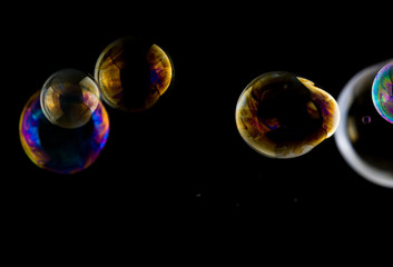 Multicolored soap bubbles close up on a black background, similar to planets