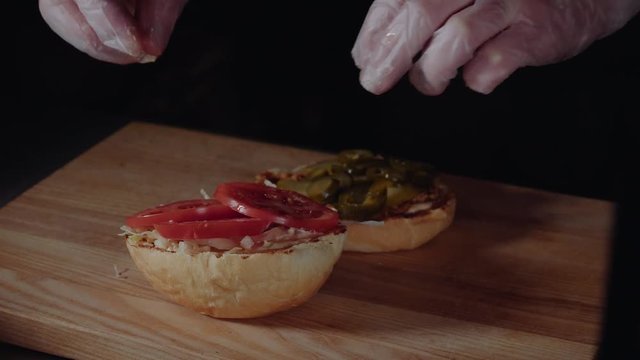 Chef preparing the burger, frying the bun on the grill, putting sliced tomatoes