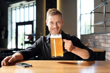 Mężczyzna pije piwo. Uśmiechnięty przystojny mężczyzna z kuflem piwa pszenicznego.