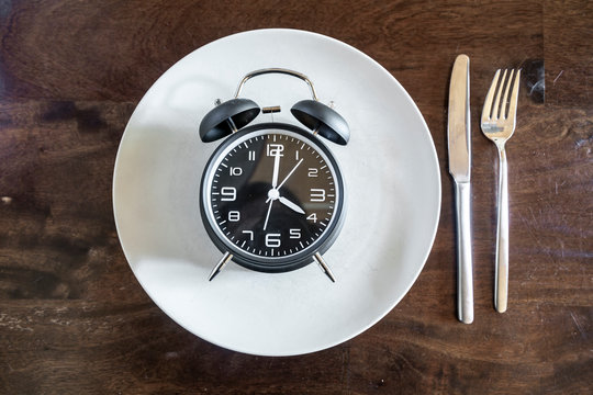 Intermittent fasting, trend : fasten, alarm clock on plate