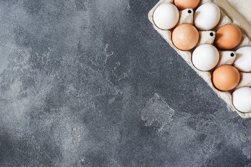 Chicken eggs in a cardboard box on a dark brutal table.