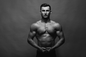 Fototapeta na wymiar Bodybuilding. Strong man posing on background. Athletic young boy showing muscles.