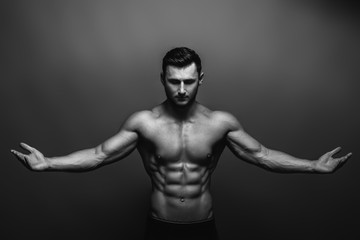 Fototapeta premium Bodybuilding. Strong man posing on background. Athletic young boy showing muscles.