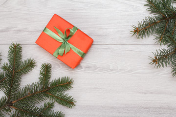 Gift box, fir tree branches on gray wooden boards