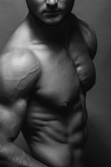 Bodybuilding. Strong man posing on background. Athletic young boy showing muscles.