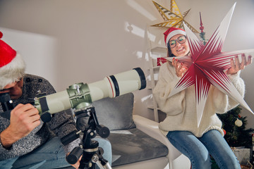 Obraz na płótnie Canvas Happy couple / friends enjoying Christmas eve / New Year's eve with telescope at home.