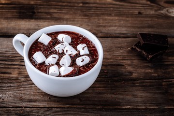 A cup of hot chocolate or cocoa with marshmallows on wooden background