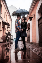 Obraz na płótnie Canvas happy loving couple is under an umbrella on a city street on a rainy day