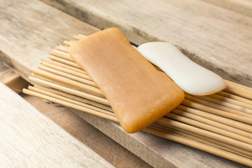 Two pieces of soap lie on a bamboo broom in a bath