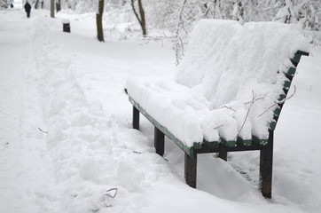 Bench covered with snow in the city park in winter. Winter landscape
