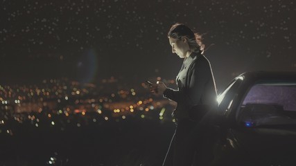Fototapeta premium portrait young woman driver stands next to a car night lights of the city