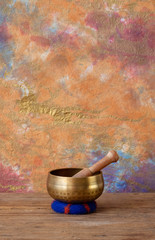 Tibetan singing bowl with wooden mallet and blue wool cushion.