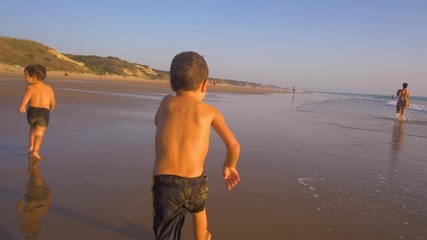 Slow motion - Two little brothers running, playing and enjoying while the camera chase them smiling and laughing