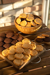 Peanut and chocolate cookies on wooden background in sun rays
