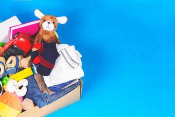 Donation box with toys, books, clothing for charity on blue background