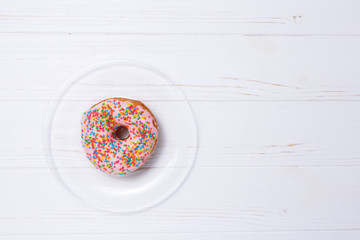 Pink donut in sugar glaze on a transparent plate