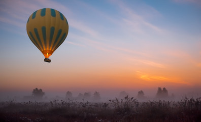 hot air balloon flying at yellow sunrise