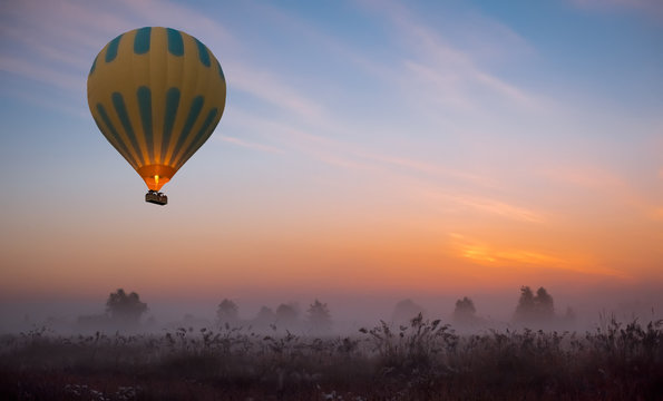 hot air balloon flying at yellow sunrise