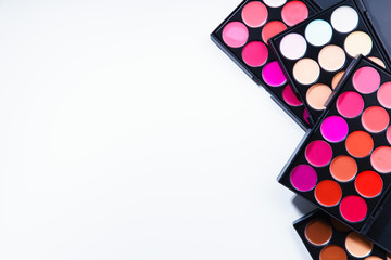 Various lipstick and eye concealer palettes with lots of colors isolated on white background. Make-up artist kit concept. Composition with copy space