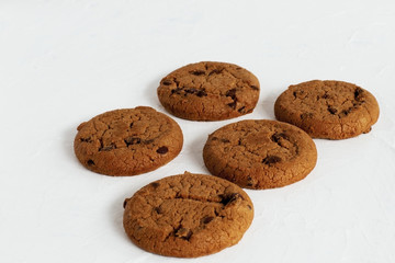 Feast of taste. Sugar ruddy shortbread homemade cookies with raisins and pieces of dark milk chocolate on a light concrete background