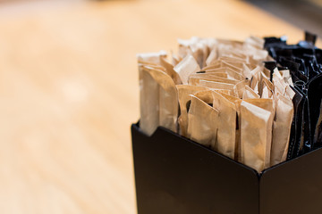 Brown sugar sachets in black box on a counter at a cafe