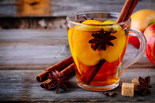 Hot mulled apple cider drink with cinnamon stick, cloves and anise