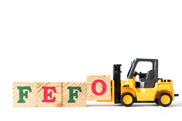 Toy forklift hold letter block o to complete word FEFO (first expired first out) on white background