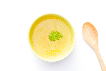Bowl of chicken broth with wooden spoon isolated on white background