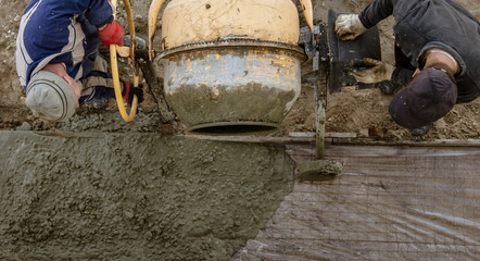 Workers pour concrete solution at a construction site