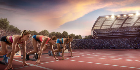 Female athletes sprinting. Three women in sport clothes on starting line prepares to run at the...