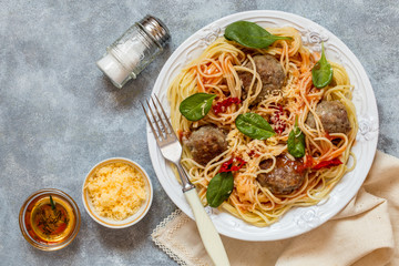 meat balls with spaghetti pasta with fresh spinach, tomatoes and cheese on a white plate
