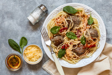 meat balls with spaghetti pasta with fresh spinach, tomatoes and cheese on a white plate