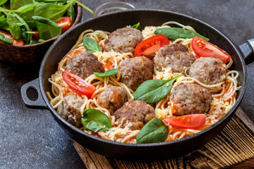 meat balls with pasta spaghetti with spinach, fresh tomatoes in a frying pan on a cutting Board