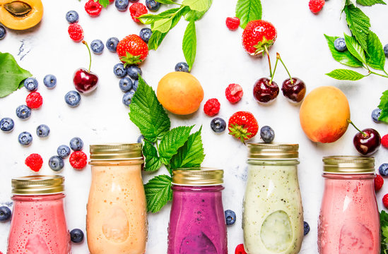 Healthy and useful colorful berry cokctalis, smoothies and milkshakes with yogurt, fresh fruit and berries on gray table, top view