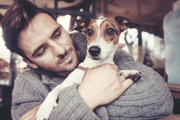 Man cuddling with his terrier dog in winter