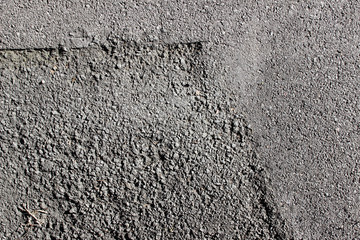 Street asphalt pavement surface texture detail with patch close up