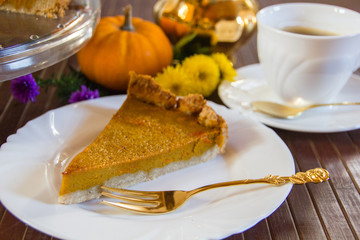 Slice of fresh home made pumpkin pie on wooden surface.  Traditionally served in fall or for thanksgiving in the United States.  Selective focus