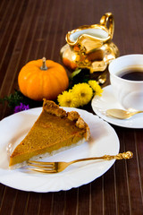 Slice of fresh home made pumpkin pie on wooden surface.  Traditionally served in fall or for thanksgiving in the United States.  Selective focus