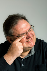 Fototapeta premium müder Mann mit Brille reibt sich die erschöpften Augen mit verzerrtem Gesicht